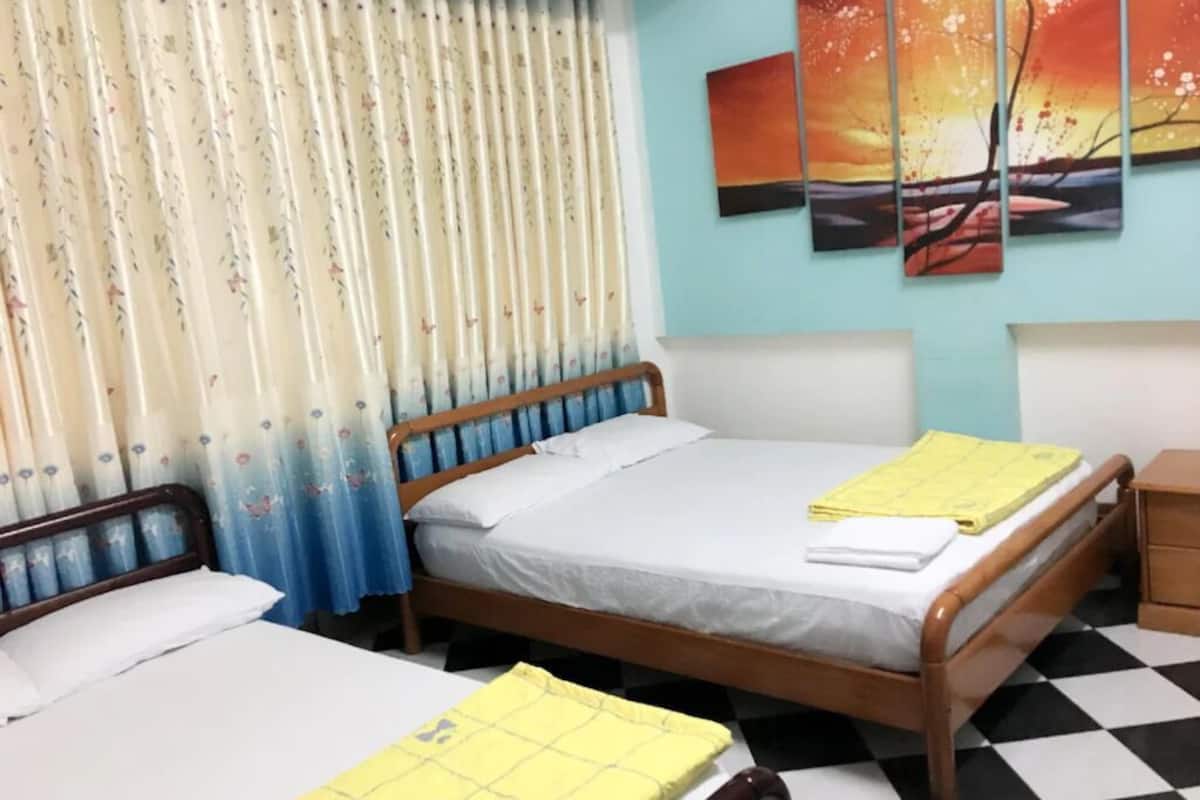 A room with two beds, a checkered floor, and a painting on the wall.