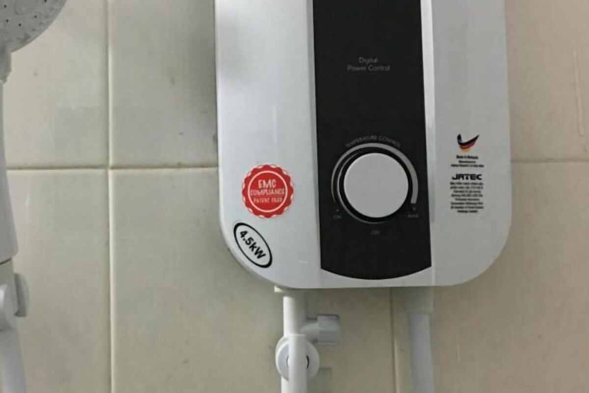 A water heater with a digital display and a red compliance sticker.
