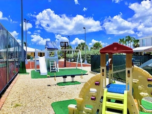 A playground with a slide, climbing structures, and a basketball court.