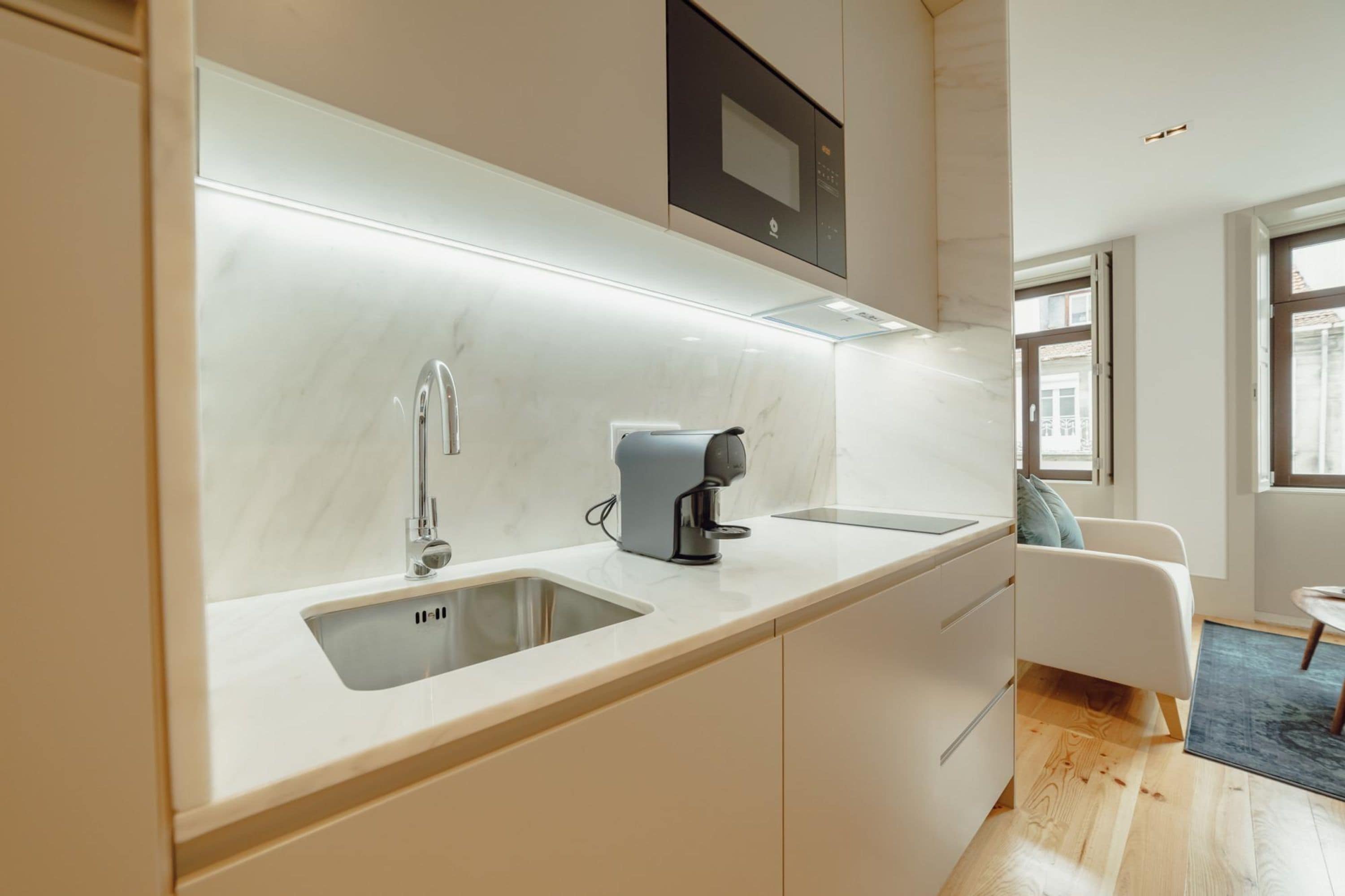 A modern kitchen with a built-in microwave, a coffee maker, and a sink.
