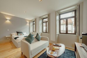 A modern room with a bed, a sofa, a coffee table, and a TV.