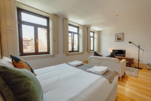 A bedroom with a large bed, two windows, a TV, and a desk. - Legacy Oporto Design Apartment H by Vacationy (Porto)