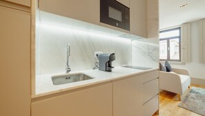 A modern kitchen with a marble countertop, a coffee machine, and a built-in microwave.