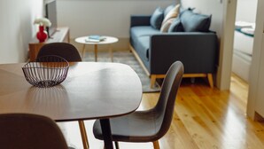 En moderne stue med en mørkegrå sofa, et rundt sofabord og et spisebord med en wirekurv.