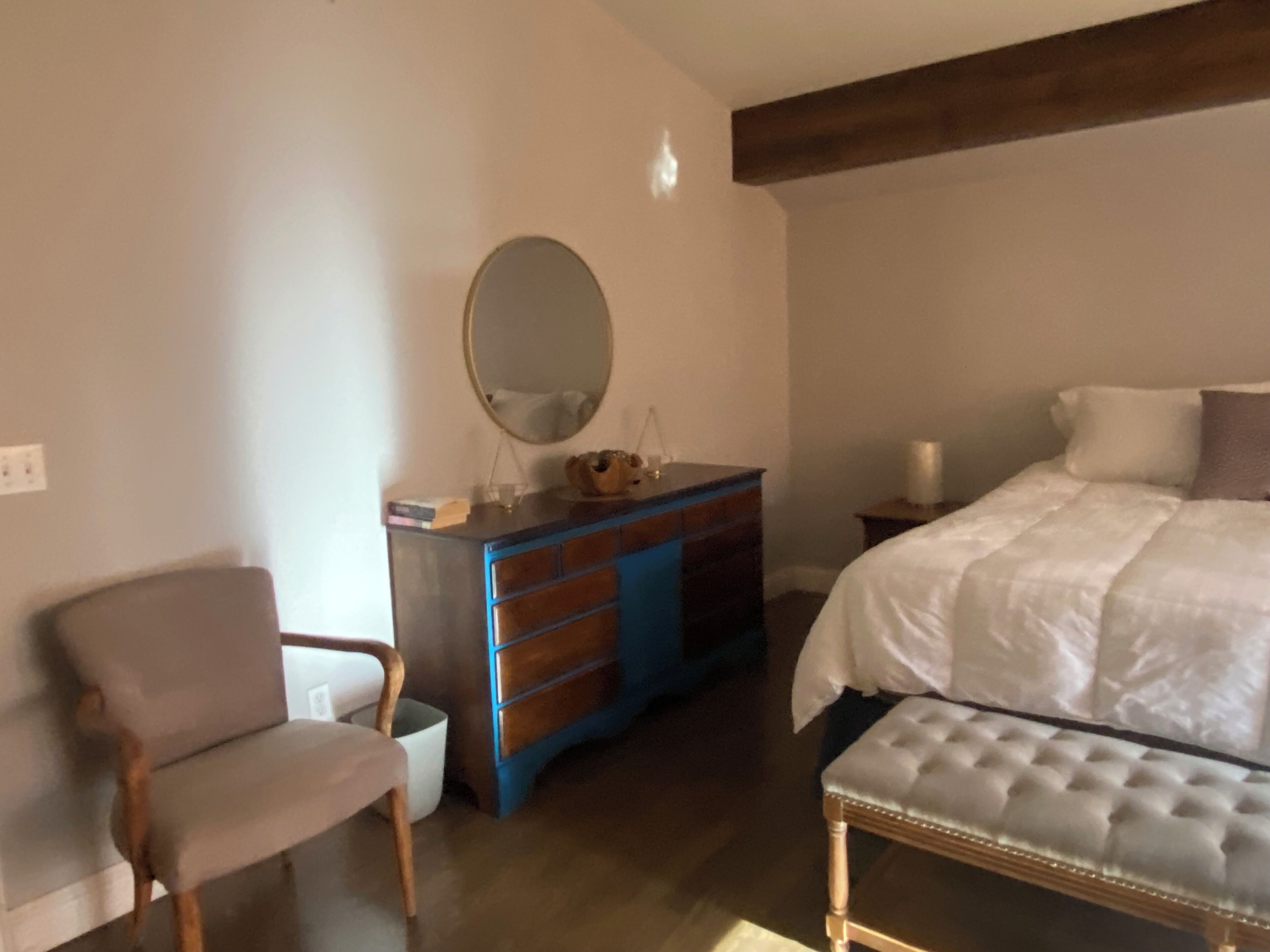 Une chambre à coucher avec un lit, une commode, une chaise et un banc.