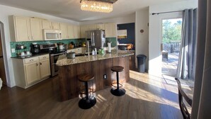 A modern kitchen with wooden cabinets, a granite countertop, and a bar stool.