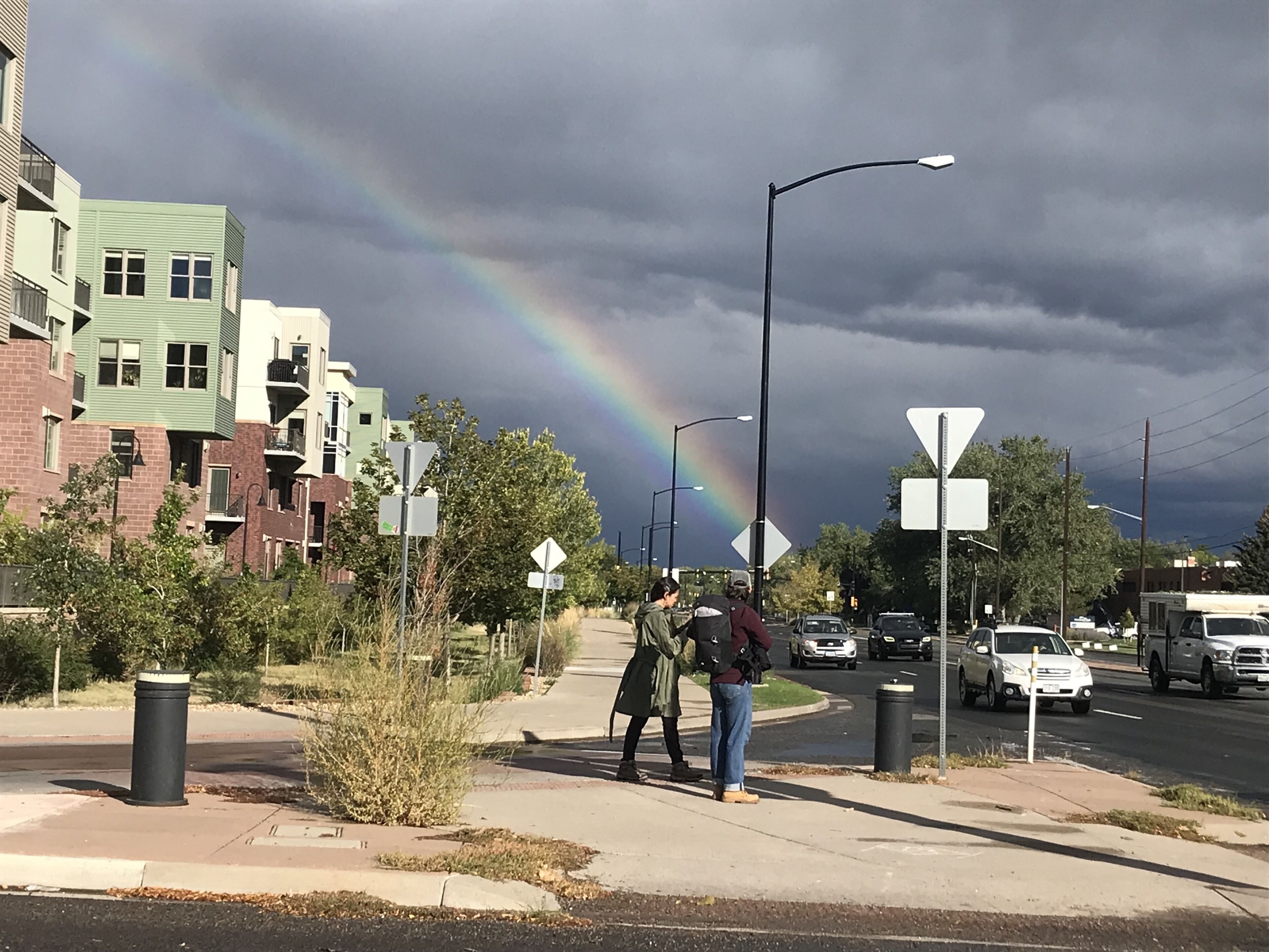 A street scene with a rainbow, buildings, and a pedestrian crossing.
