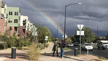 A street scene with a rainbow, buildings, and a pedestrian crossing.