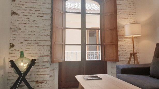 A room with a wooden door, a table, a lamp, and a sofa. - Picasso neighborhood. Beautiful flat in central 2B (Málaga)