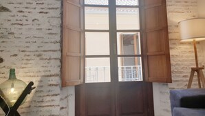 A room with a large wooden door, a white brick wall, and a lamp. - Picasso neighborhood. Beautiful flat in central 2B (Málaga)