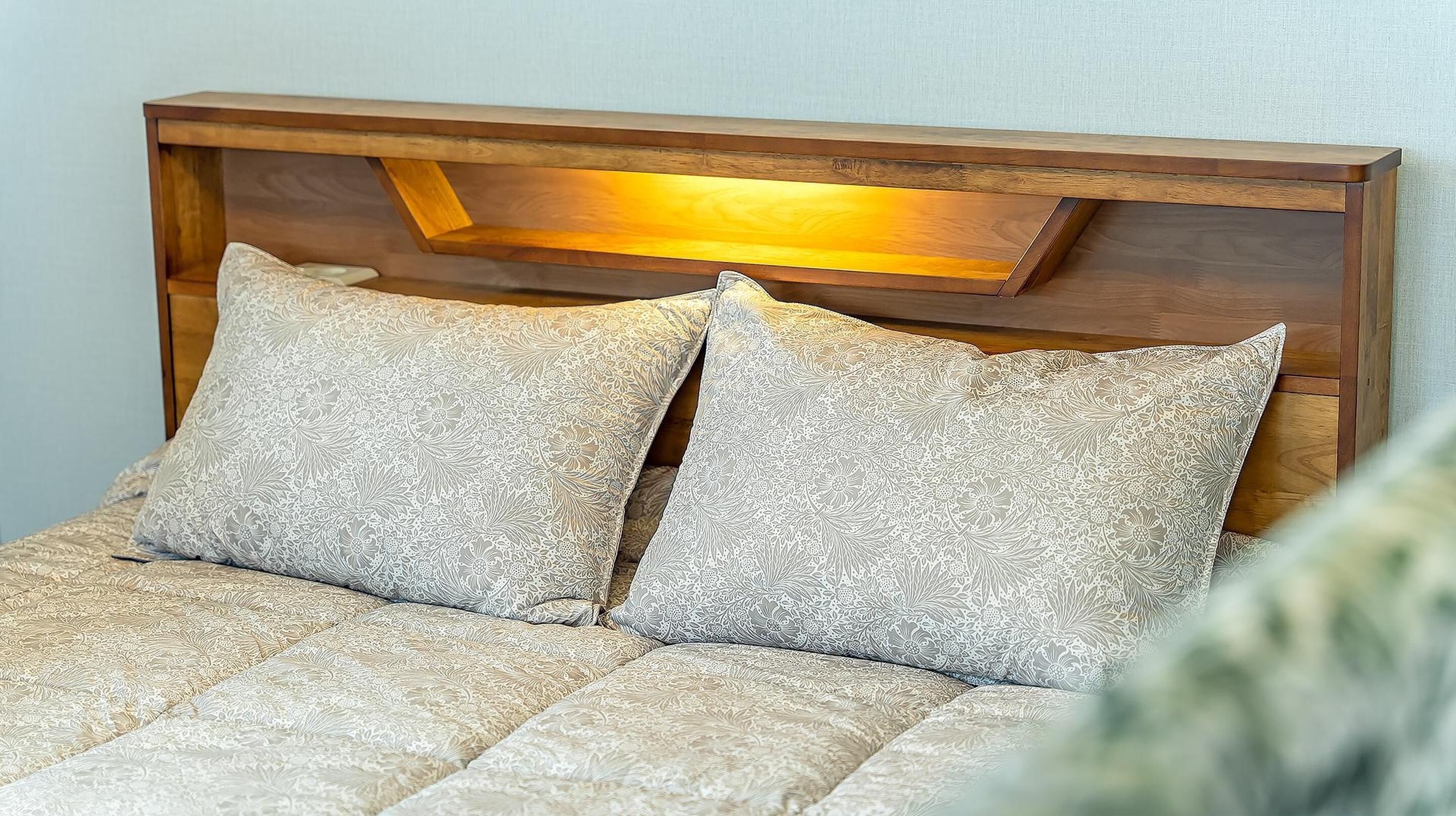 A bed with a wooden headboard and two patterned pillows.