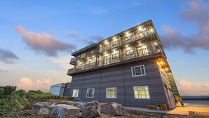 A multi-story building with balconies, large windows, and a coastal view. - Jeju Hoyeongfarm Stay (Jeju City)