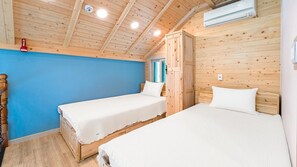 Ein blockhausähnliches Zimmer mit zwei Holzbett, einer blauen Wand und einer Holzkοννe mit eingelassener Beleuchtung.