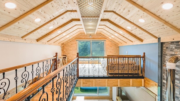 A wooden interior with a staircase, wooden walls, and a window overlooking greenery.