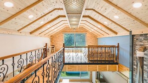 Een houten interieur met een trap, houten wanden en een raam met uitzicht op groen.