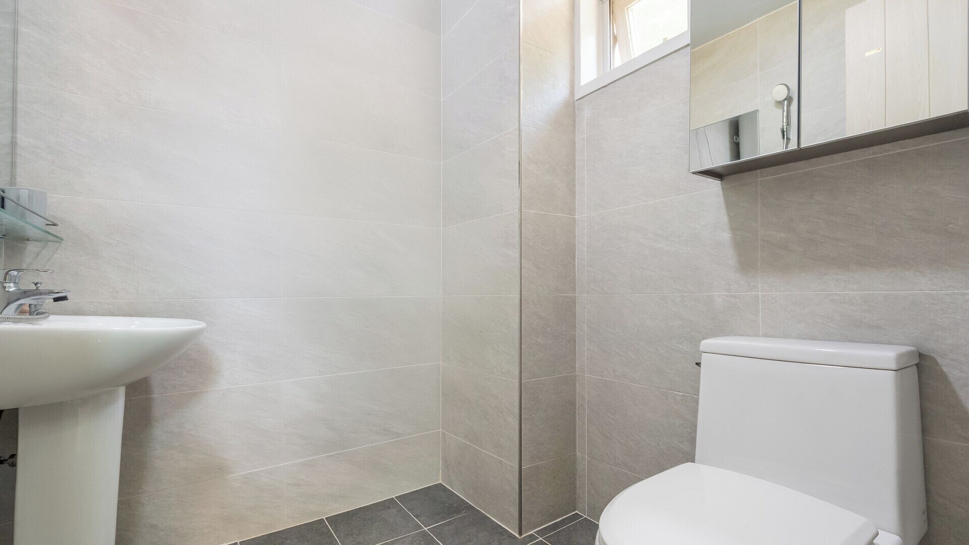 A bathroom with a white sink, a toilet, and a mirror above the sink.