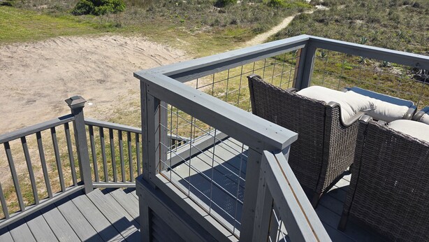 A wooden deck with wicker furniture overlooking a beach. - Beach front cottage - don't let the outside fool you - check out the photos!  (Fernandina Beach)
