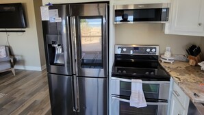 A kitchen with stainless steel appliances, white cabinetry, and a wooden floor. - Beach front cottage - don't let the outside fool you - check out the photos!  (Fernandina Beach)