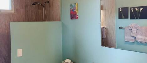 A bathroom with a wooden ceiling, a toilet, a sink, and a shower.