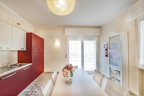 Une cuisine moderne avec des meubles rouges, un plan de travail blanc et un vase rempli de fleurs sur la table.