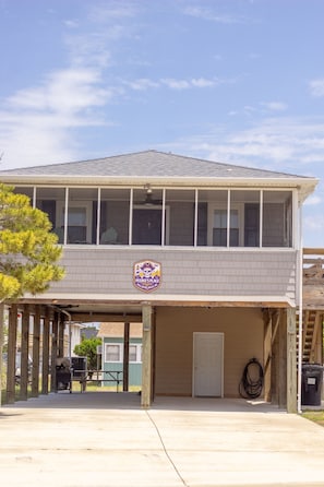 A two-story building with a covered parking area, a sign indicating a pet-friendly establishment, and a visible door.