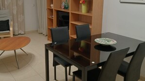 A dining area with a table and chairs, a bookshelf, and a painting on the wall. - A&N Valle Niza (Benajarafe)