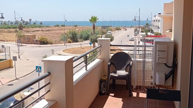 A balcony with a view of the sea, a chair, a table, and a water heater. - A&N Valle Niza (Benajarafe)