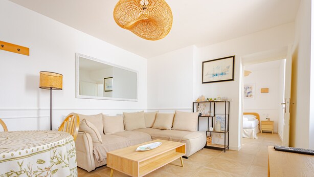A living room with a sofa, a coffee table, a lamp, a mirror, and a bookshelf.