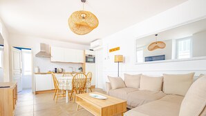 A modern living room with a sofa, a wooden coffee table, and a dining area with chairs and a table.