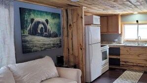 Une cuisine de taille réduite, dotée de meubles en bois, d’un réfrigérateur et d’une fenêtre laissant entrer la lumière naturelle.