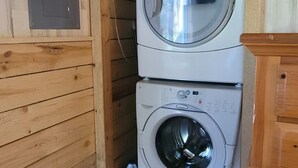 Une buanderie équipée de deux machines à laver à chargement frontal superposées, avec des murs et un meuble en bois.