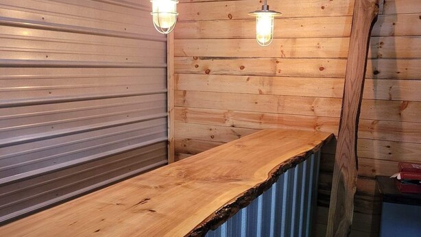 Un intérieur en bois avec un comptoir en métal et des luminaires suspendus.