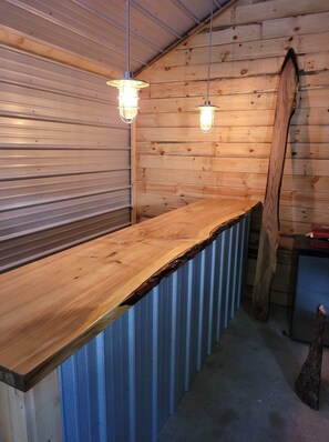 A wooden interior with a metal counter and hanging light fixtures. - Pine Acres Getaway, 10 acres of fun and relaxation. (Grayling)