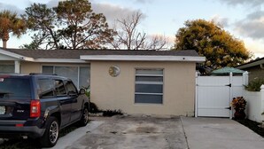 Un garage attenant à une maison, dans lequel est garé un VUS, avec une allée fermée par un portail et un petit bâtiment doté d’une porte de garage.