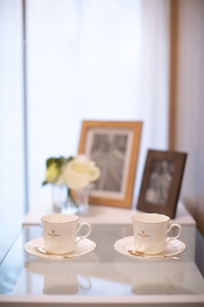 Deux tasses blanches ornées d’un bord doré, posées sur une surface réfléchissante.