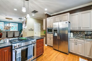 A modern kitchen with stainless steel appliances, wooden cabinets, and a central island. - Lake Norman Cove Home w/ Golf Sim & Kayaks (Sherrills Ford)