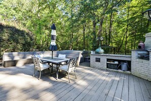 A wooden deck with a table and chairs, a grill, and a trash can. - Lake Norman Cove Home w/ Golf Sim & Kayaks (Sherrills Ford)