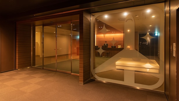 Un moderno vestíbulo de hotel con mostrador de recepción, puertas de cristal y zona de registro.