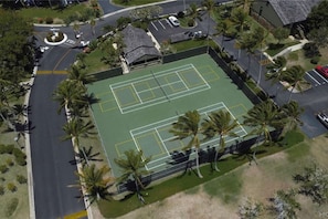 Tennis enthusiasts can enjoy a game on the well-maintained court surrounded by palm trees.