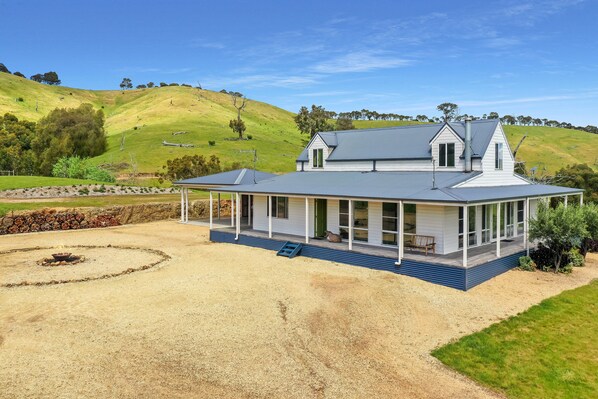 A two-story house with a covered porch, a fire pit, and a view of rolling hills. - Manandel - Rural Retreat (Bonnie Doon)