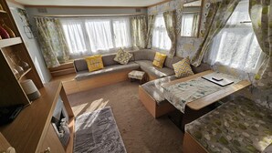 Ein gemütliches Wohnmobil-Interieur mit einer Sitzecke, einem kleinen Tisch und einem Fenster mit Vorhängen.