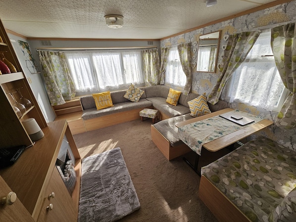 A cozy RV interior with a sofa, a small table, and a window with curtains.