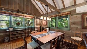 Un comedor rústico con vigas de madera, una mesa grande y sillas.