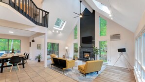 Un salón amplio con techo alto, chimenea y comedor con mesa y sillas.