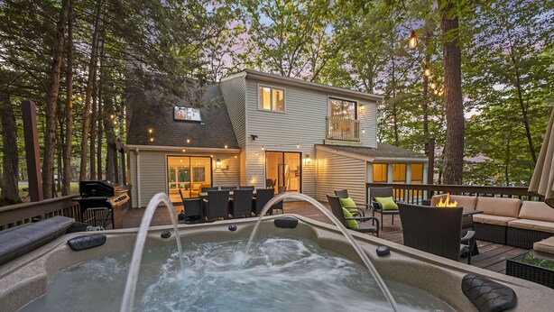 Un jacuzzi con caída de agua, rodeado de muebles de exterior y una terraza.