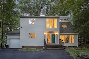 A two-story house with a garage, a front porch, and a staircase leading to the entrance.