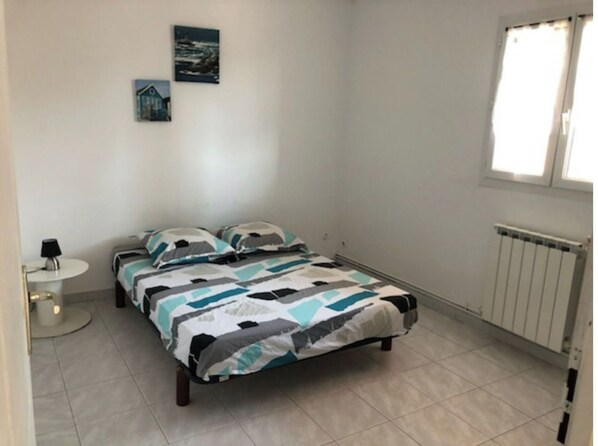 Une chambre à coucher avec un lit, une table de chevet, une lampe et une fenêtre.
