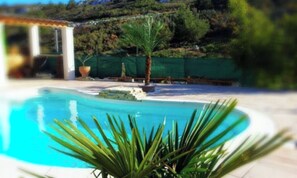 Une piscine à l’eau d’un bleu cristallin, entourée d’une terrasse blanche.
