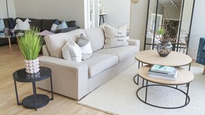 Ein modernes Wohnzimmer mit einer Couch, einem Couchtisch und einem Beistelltisch mit einer Vase.