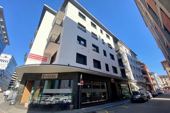 A multi-story building with a 'SUGAR' sign at the ground level, indicating a restaurant or cafe. - Boutique Apartment 10, Lugano, Switzerland (Lugano)